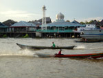 Klotoks speeding down the river at Pangkalan Bun, Mosque in background